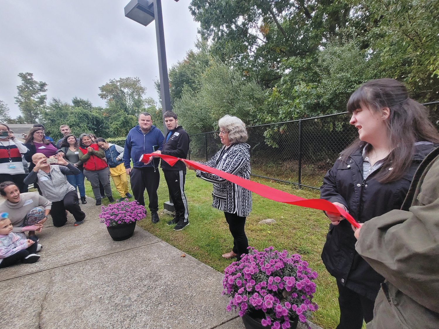 RIBBON SPLIT: Longtime Unity Community member’s mother, Maria DeSimone, snipped the red ribbon in half, and the TAP community garden was officially open.